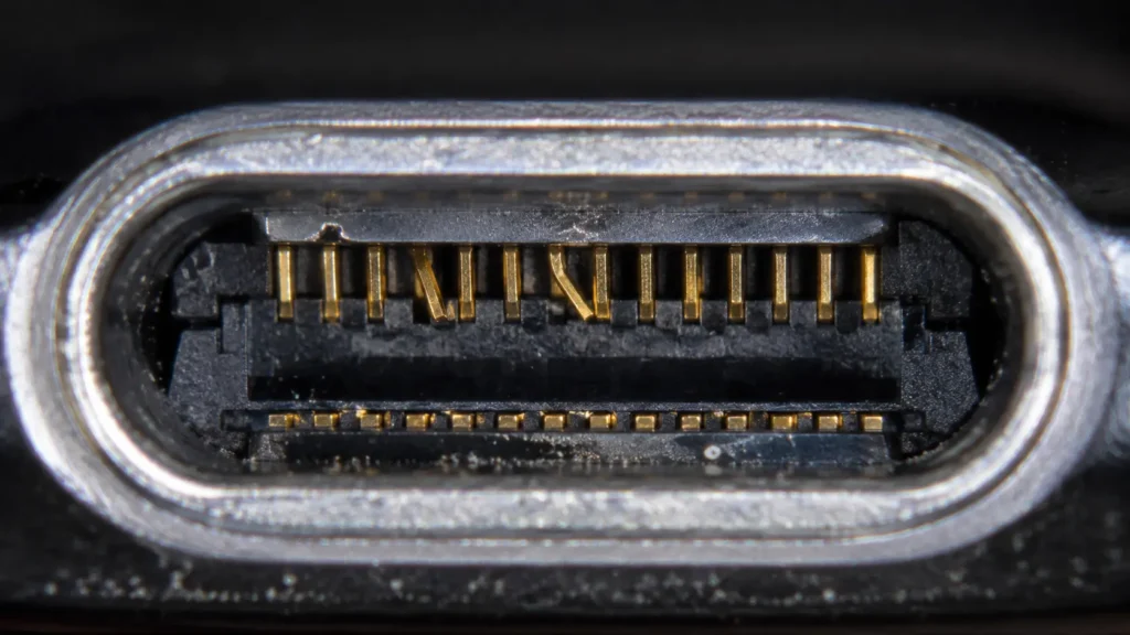 Magnified view of a smartphone charging port showing bent metal pins inside